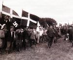 grænseland. Feltgudstjeneste ved det danske nationalsocialistiske landsmøde i Aabenraa i 1934.  Partifører Frits Clausen synger for.  Det danske uniformsforbud fra april  1933 sætter sit præg på forsamlingen, der er væsentlig mindre disciplineret  at skue end i en tilsvarende situation  i Hitlers Tyskland. Foto: Fra bogens  forside/Museum Sønderjylland 
