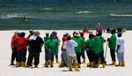Strandvaskere. Oprydningsarbejdere hyret af BP står på stranden i Perdido Keys, Florida. Olieudslippet har fået tusindvis af frivillige til at melde sig, men BP vil kun bruge faglærte folk til at håndtere olieforureningen. 