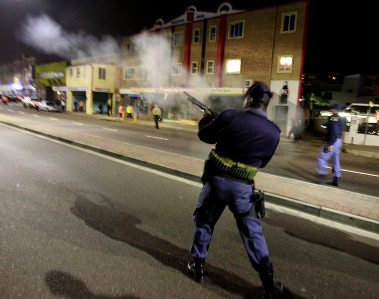 Advarsel. En sydafrikansk politibetjent skyder tåregas mod demonstranter ved VM-stadionet i Durban. 