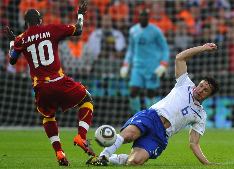 oprydderen. Hollands Mark van Bommel i klassisk stil med en fejende tackling mod Ghanas Stephen Appiah under en testkamp. Arkivfoto. 