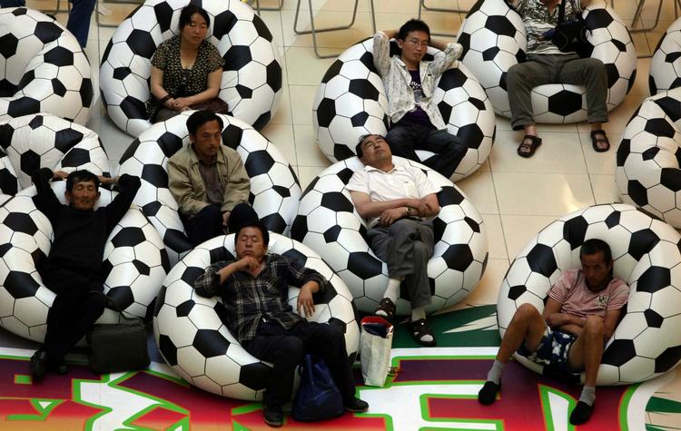 Kiggere. Kinesere ser fodbold i et indkøbscenter i Beijing. Efter ansigtsudtrykkene at dømme er det nok ikke en af VM's mest vilde kampe. 