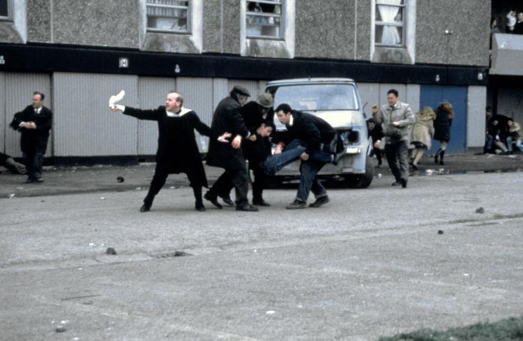 Fred. En præst forsøger at få de britiske soldater til at  stoppe skyderiet mod ubevæbnede civile ved at bruge et lommetørklæde som hvidt flag, så en dødeligt såret ung mand kan  blive båret væk fra nedslagtningen. Foto fra filmen 'Bloody Sunday'. 