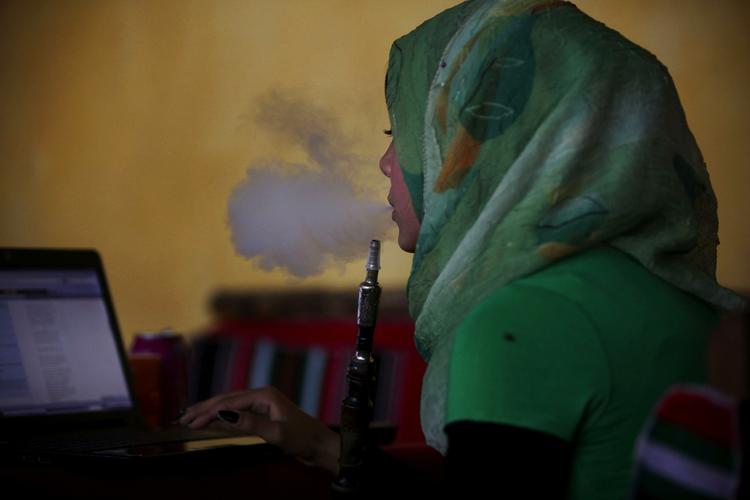 Forbudt. En palæstinensisk kvinde ryger vandpige, mens hun er på internettet i en café i Gaza City. Men det skal være slut nu, mener Hamas, der forbyder kvinder at ryge vandpibe i offentligheden. 