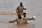 Oversvømmelser. Mænd vader igennem gaderne i Pabbi i det nordvestlige Pakistan. 