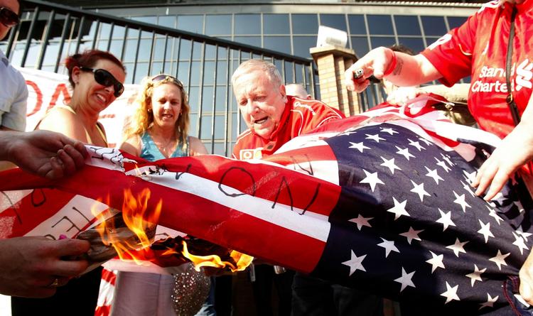 flagafbrænding. Liverpool-tilhængere brænder amerikanske flag af uden for hjemmebanen Anfield i en protest mod klubbens ejere. Arkivfoto. 