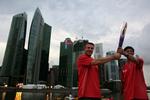 Ildsjæle. Den mangedobbelte verdensmester i stangspring, Sergei Bubka (tv.) overtager den olympiske fakkel fra Eugene Heng foran Singapores skyline. 