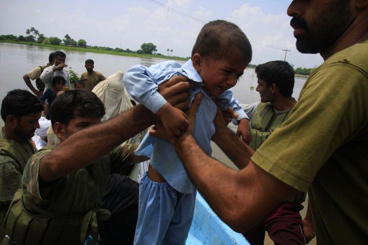 redningsindsats. En lille dreng og andre indbyggere i en landsby i Khangarh nær Multan i Pakistan bliver hjulpet væk fra de oversvømmede områder af pakistanske regeringssoldater. 