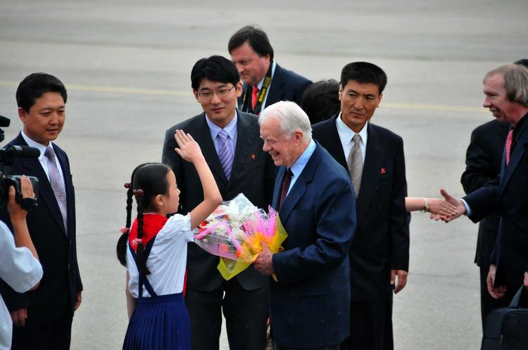 Velkommen. Jimmy Carter modtages af officielle nordkoreanere samt en lille pige, da han ankommer i Pyongyang tidligere i dag. 