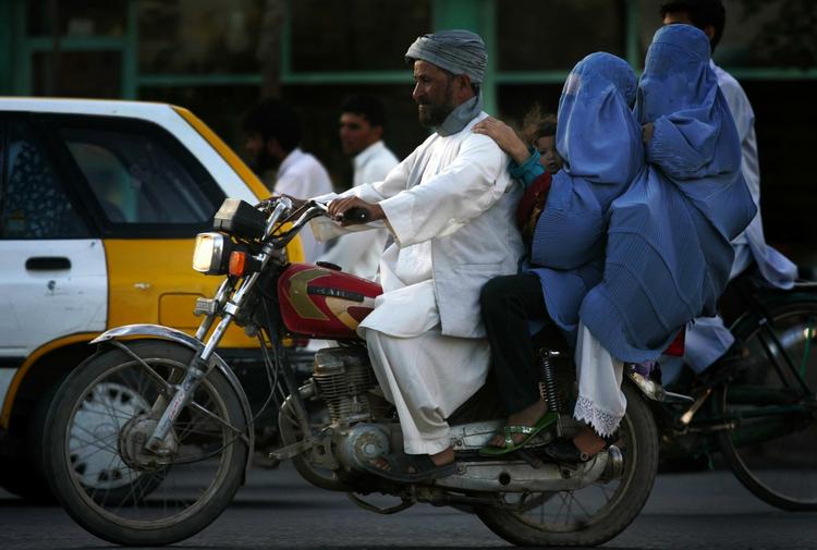 Formummede. En afghansk mand kører gennem Herat ved for Kabul med to burkaklædte kvinder. 