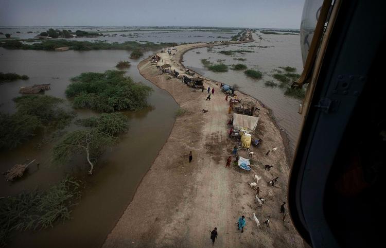 oversvømmelser. En helikopter fra den pakistanske hær flyver over flygtninge, der er søgt  i sikkerhed på en dæmning nær byen Thatta. 
