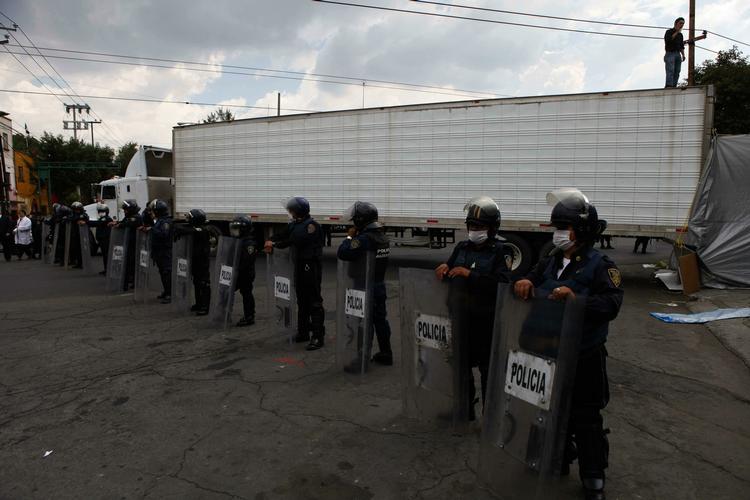 Sikkerhed. Maskerede politifolk bevogter den lastvogn med 72 lig, som ankommer til et lighus i Mexico City. 