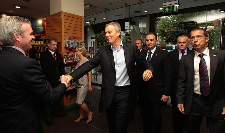 velkommen. Tony Blair hilser på ejeren af den boghandel i Dublin, hvor han i dag signerer bøger.  Uden for butikken var der vrede demonstranter. 