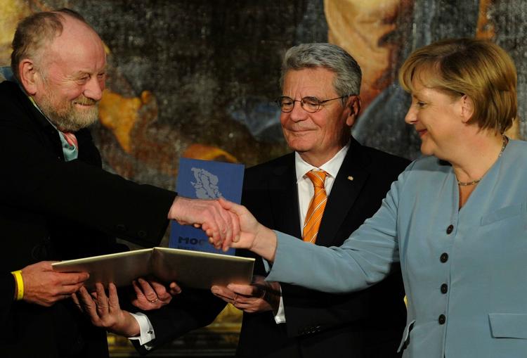 Prisoverrækkelse. Det tyske dagblad, Frankfurter Algemeine, mener,  at Merkel løb en kæmperisiko ved at lade sig fotografere sammen med den danske tegner. 