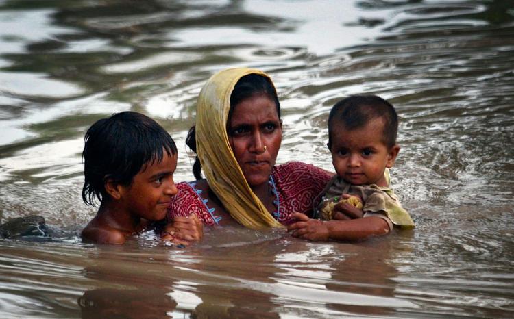 oversvømmet. En pakistansk mor bærer sine børn gennem et oversvømmet område i Pakistan. Foto: K.M.Chaudary/AP 