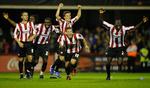 sensation. Brentford-spillere løber jublende mod banens midte efter det sidste straffespark i den overraskende sejr i Carling Cup. 
