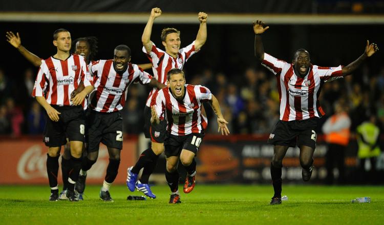 sensation. Brentford-spillere løber jublende mod banens midte efter det sidste straffespark i den overraskende sejr i Carling Cup. 