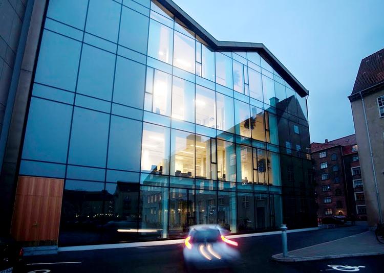 Om dagen spejler omgivelserne  sig i glasfacaden, men når det bliver  mørkt, kan forbipasserende se,  hvad der foregår bag facaden. 