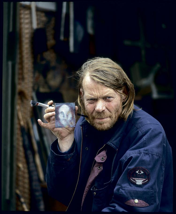 William Skotte Olsen. Født 1945. Død 2005. I sine sidste år malede han i et hæsblæsende tempo. Blandt andet et hav af portrætter på bølgepap, tagplader eller andre former for affald, han fandt. Foto fra udstillingskataloget: Simon Lautrop 