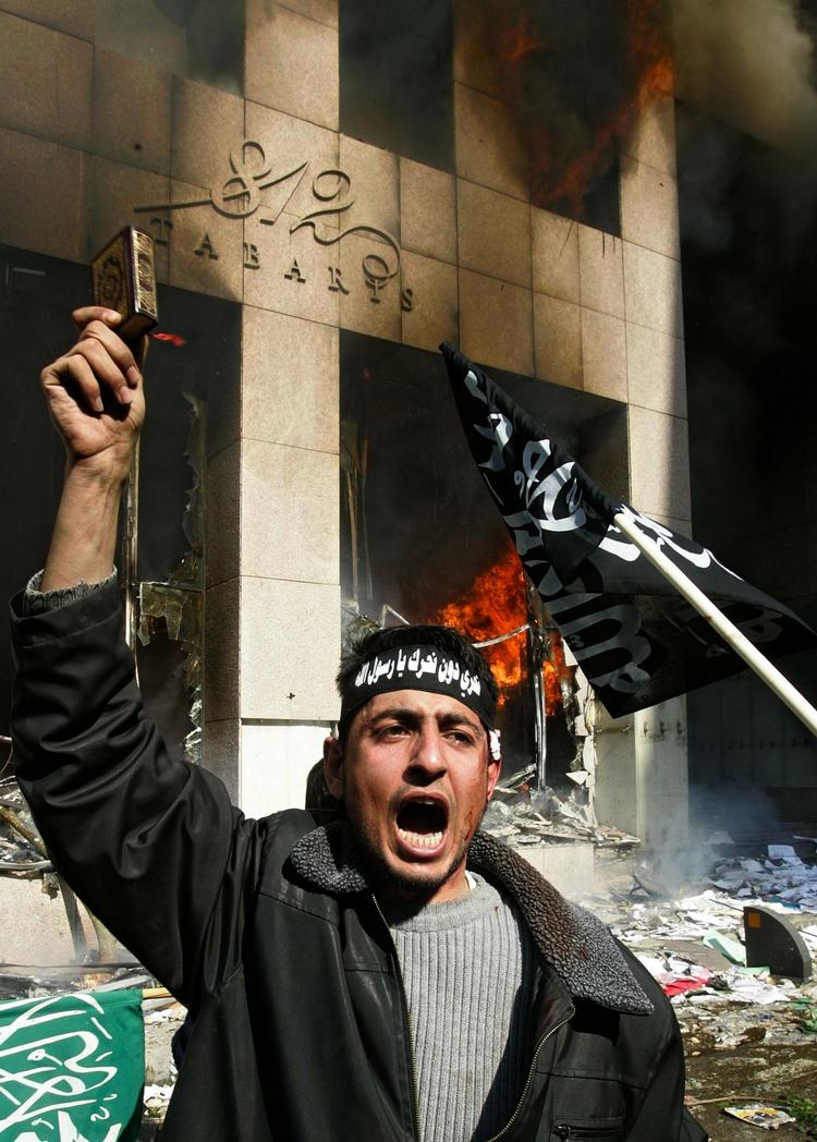 En af demonstranterne holder symbolsk koranen op foran det brændende danske konsulat. 