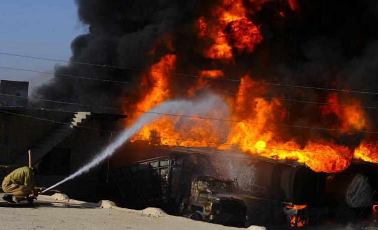 ANGREB. Brandmand forsøger at slukke ilden i brændende tankvogne efter onsdagens angreb. 