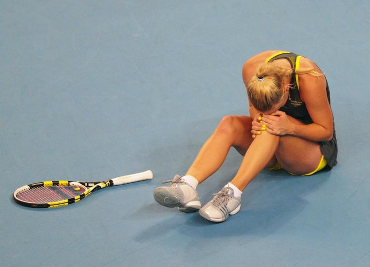 TENNISCHOK. Caroline Wozniacki gik i går til tops på verdensranglisten. I dag lå hun på jorden efter et vrid i knæet. 