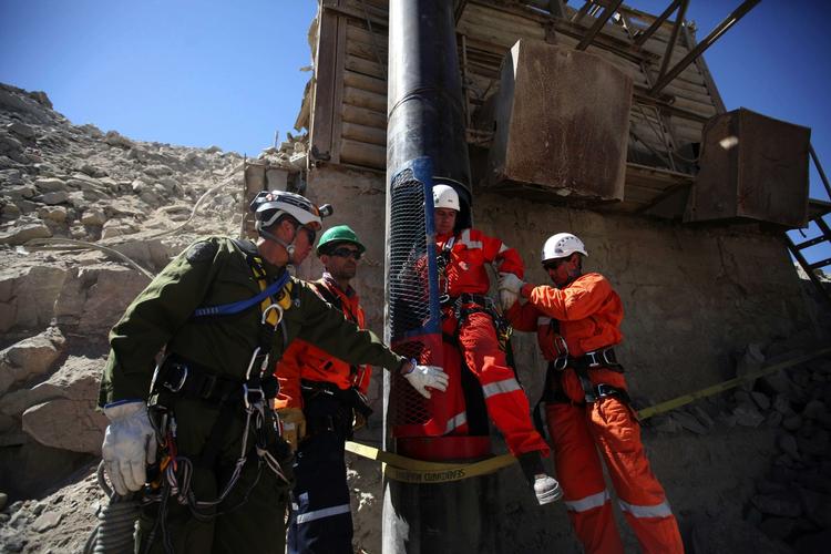 Redningsmandskab hjælper en kollega ud af den redningskapsel der skal redde de 33 minearbejdere op. 