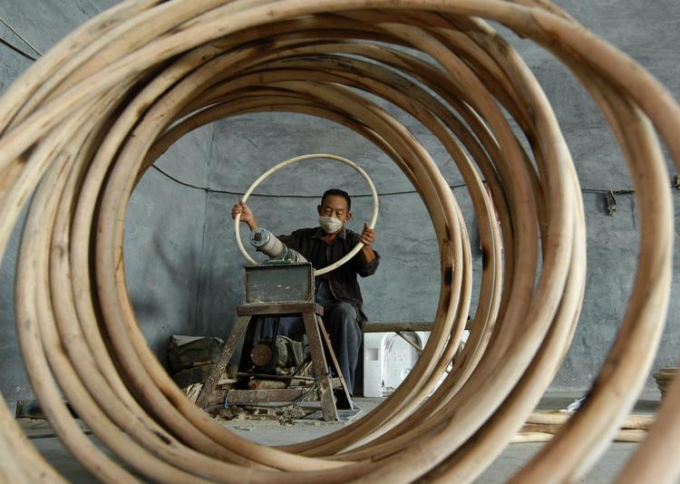 lavprisindustri. En kinesisk mand er i gang med rattanrør på møbelfabrik i Kina, hvis billige varer oversvømmer USA. 