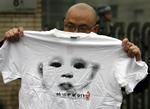 Protest. Zhao Llianhai har også designet protest T-shirts. Her holder en anden vred kineser en af hans trøjer ved en demonstration uden for en retsbygning i Beijing i marts i år. 
