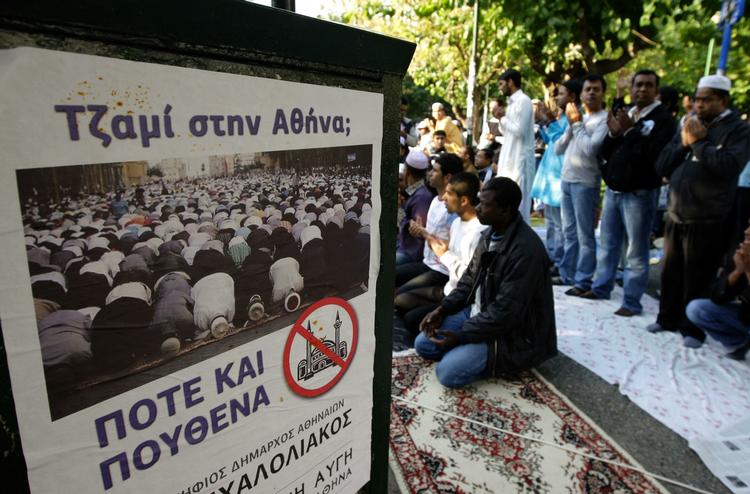 Konflikt. En plakat proklamerer 'Moskeer i Athen: Ingen steder og aldrig' mens muslimerne samles til udendørs bøn. 
