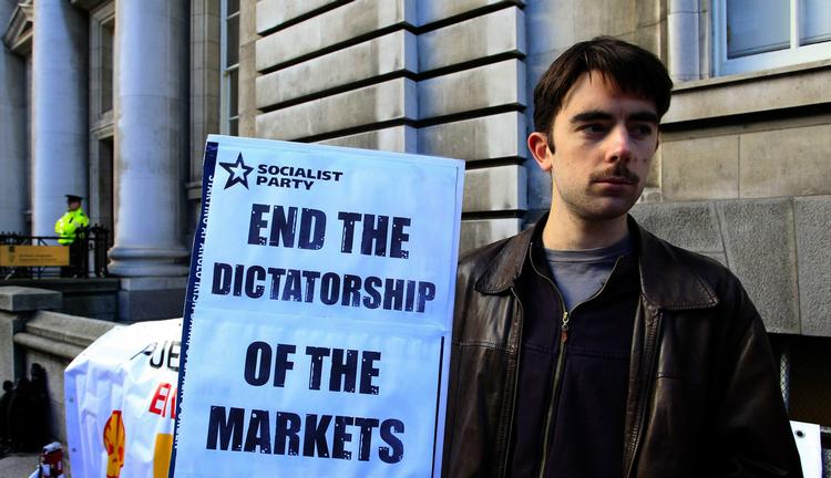 Diktaturstat. 'Slut markedernes diktatur' står der på plakaten, som denne irer luftede i Dublin i torsdags. 