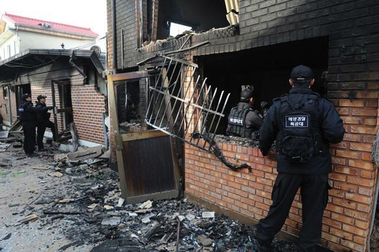 Medlemmer af Sydkoreas kystvagt kigger nærmere på de ødelagte huse. 