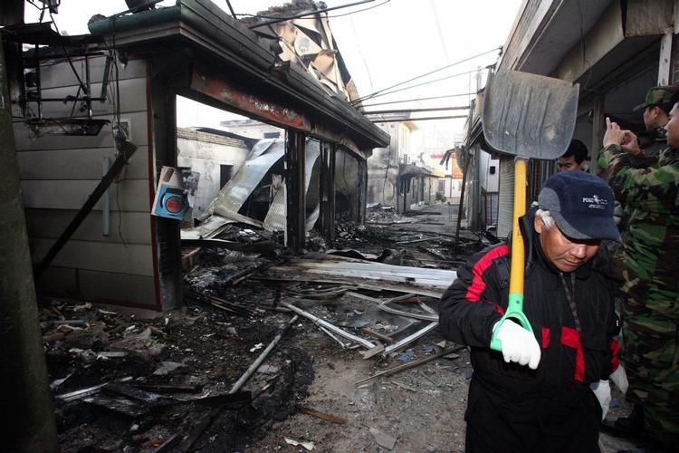 En indbygger på øen Yeonpyong går mellem ruinerne. 