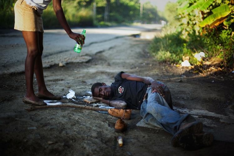 Syg. En nabo giver vand til den 30-årige Antonio Joseph, som ligger syg af kolera ved en vej i udkanten af byen Cap Haitien. 