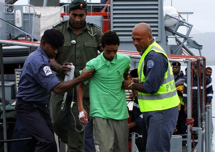 Landfast. Den ene af de tre teenagedrenge hjælpes i land på Stanley Brown flådebasen i Suva på Fiji-øerne. 