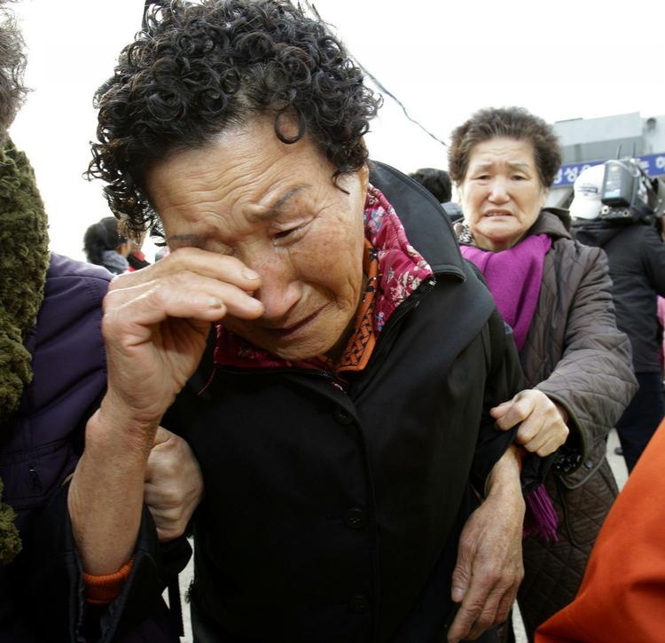 To grædende kvinder fra øen Yeonpyong ankommer til havnen i Incheon vest for Sydkoreas hovedstad Seoul. 