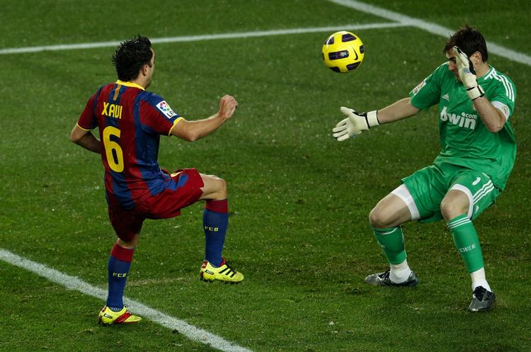 Barcelonas Xavi Hernandez løfter bolden over Real Madrids målmand Iker Casillas. 