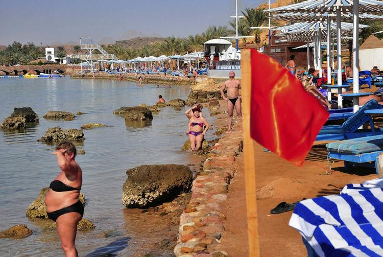 Badeforbud. Sharm el-Sheikh i dag. Turister solbader og spejder ud over havet, mens det røde flag signalerer badeforbud efter flerer hajangreb. 