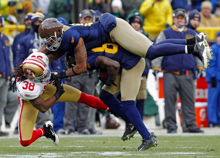 effektivt. Green Bay Packers' Andrew Quarless (øverst) hindrer San Francisco 49ers  Dashon Goldson (38) i at komme frem til bolden, mens Donald Driver (80) bliver midten i en sandwich. 