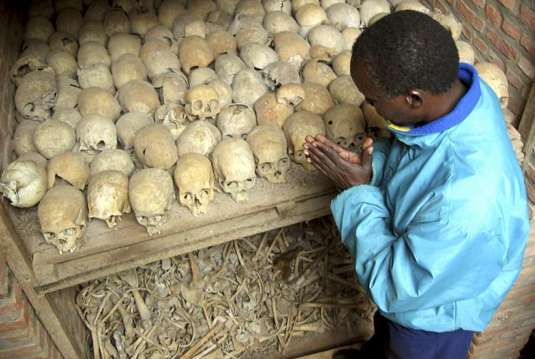 A Rwandan prays over the bones of genocide victims at a mass grave in Nyamata, Rwanda. Archive. 
