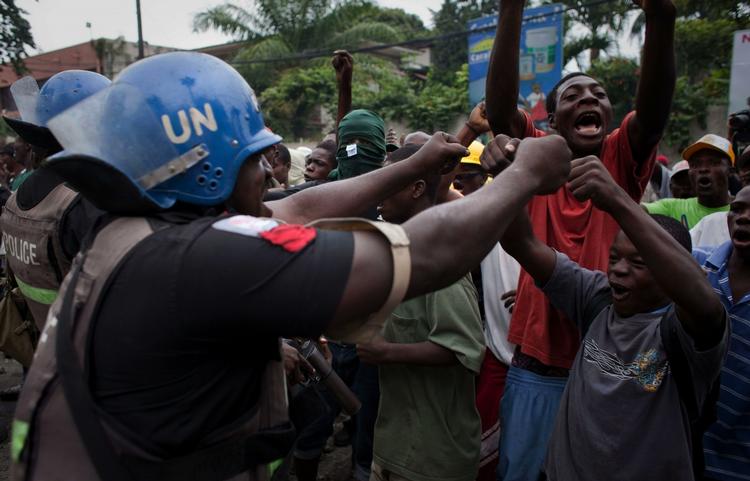 'Fist bump'. Efter flere dage med optøjer kunne demonstranter i aftes juble over, at stemmerne bliver genoptalt. En nigeriansk, fredsbevarende soldat tager del i jublen. 