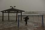 bølger. Et barn i Tel Aviv har trodset elementernes rasen og leger på stranden. 