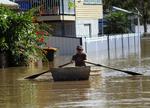 Gadesejlads. En mand er på vej hen ad en gade i Rockhampton, Queensland. Byen, der har 75.000 indbyggere, er næsten isoleret fra omverdenen på grund af vandmasserne. 