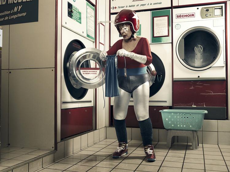 superhelt. Bedstemor skulle ikke gå og være ked af det, tænkte reklamefotografen Sacha Goldberger, og for at muntre hende op, begyndte han at tage billeder af hende som figuren Super Mamika. Her ser vi hende en helt almindelig dag på vaskeriet. 
