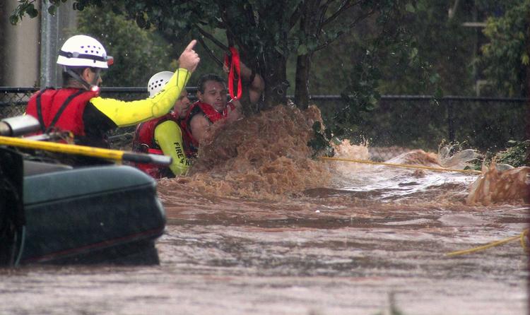 Naturkastrofe. En mand klynger sig til et træ i Toowoomba vest for Brisbane, mens redningsarbejdere prøver at komme ham til undsætning. 