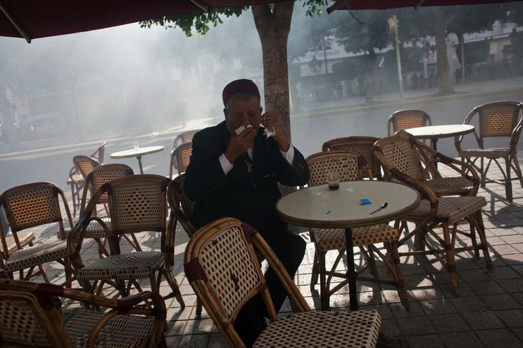 Dagligliv. En ældre tuneser prøver at trække vejret for tåregas gennem et lommetørklæde ved et cafebord på Avenue Bourguiba, hovedgaden i det centrale Tunis. 