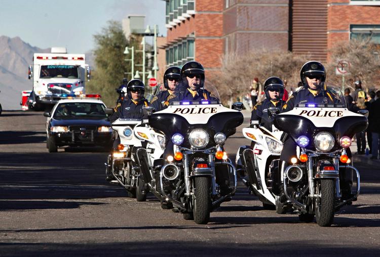 Skudoffer. En hel kortege sørgede for, at Gabrielle Giffords kom sikkert ud af hospitalet i Tuscon. 