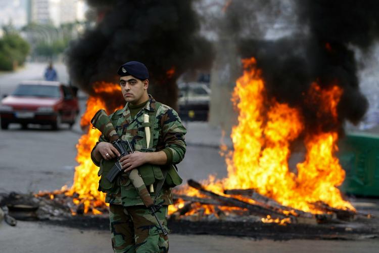 OPTØJER. Libanesisk soldat foran brændende dæk, antændt af demonstranter i Beirut  protest mod den nye ministerpræsident. 