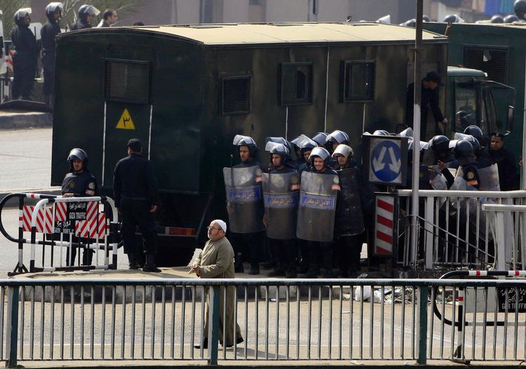 En ældre egyptisk mand passerer egyptiske sikkerhedsstyrker under sammenstødene mellem demonstranter og politi efter dagens fredagsbøn. 