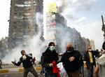 Egyptiske demonstranter flygter, idet urobetjente affyrer tåregas i Kairo. 