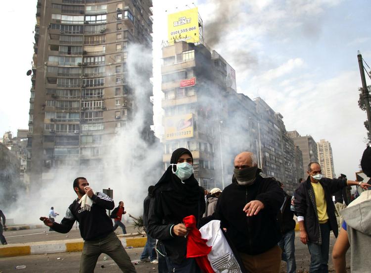 Egyptiske demonstranter flygter, idet urobetjente affyrer tåregas i Kairo. 